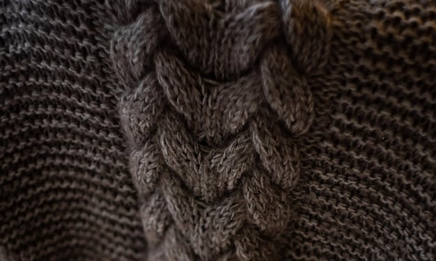 A close-up shot of different types of knitwear (wool, cashmere, acrylic blend) with a hand touching the fabric to show texture and quality. Focus on the different weaves and materials.