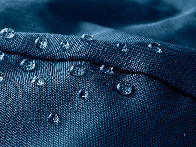 Close-up shot of the fabric of a Nike outdoor jacket, highlighting its waterproof and breathable properties. Water droplets are visible on the surface, demonstrating the jacket's water resistance.