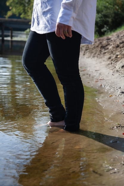A person wearing Nike outdoor pants wading through a shallow stream. The pants are shown to be water-resistant and quick-drying, highlighting their practicality in wet conditions.