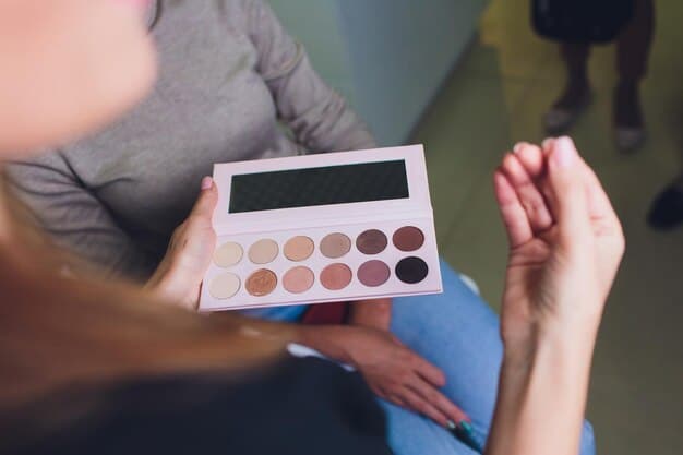 A hand swatching different shades from an eyeshadow palette on fair skin. The swatches display a range of colors from warm neutrals to cool tones, highlighting the pigment and texture of each shade.
