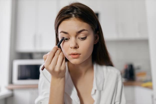 A woman applying black liquid eyeliner to her upper eyelid, creating a classic cat eye flick at the outer corner of her eye. Her other eye is open, showing the completed eyeliner look.