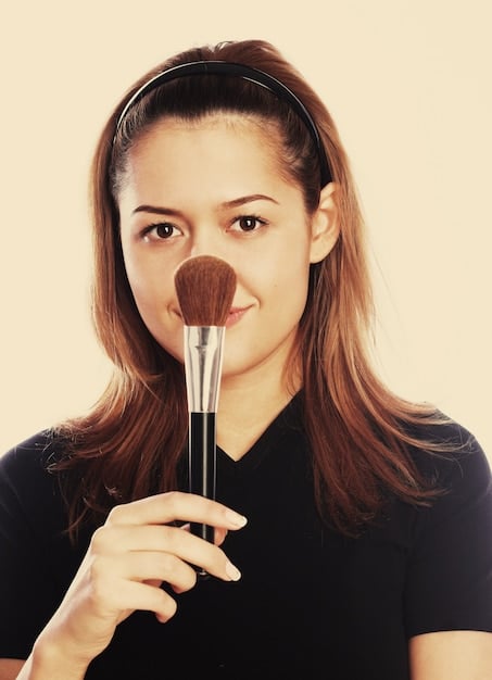 A makeup artist applying blush on a model's cheek with a fluffy brush, demonstrating a proper blush application technique.